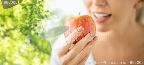 Image of close up of woman eating ripe red apple in summer