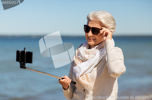 Image of senior woman taking selfie on beach