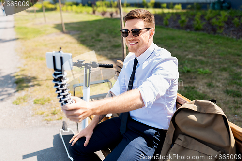 Image of businessman taking selfie by smartphone in city