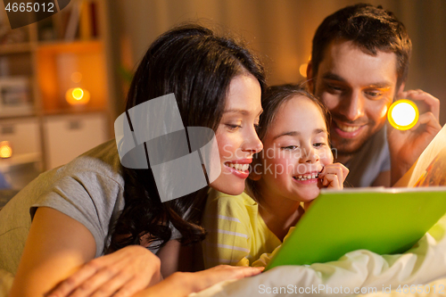 Image of happy family reading book in bed at night at home