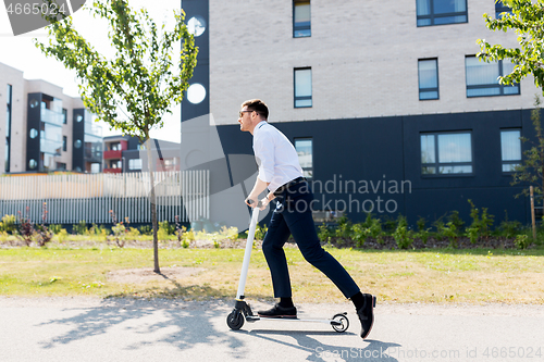 Image of young businessman riding electric scooter outdoors