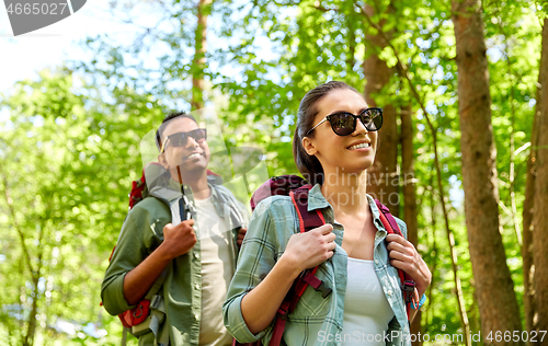 Image of mixed race couple with backpacks hiking in forest