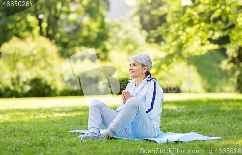 Image of happy senior woman doing yoga at summer park