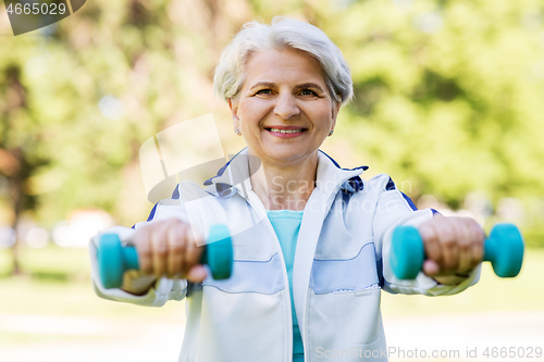 Image of senior woman with dumbbells exercising at park