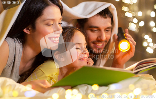 Image of happy family reading book in bed at night at home