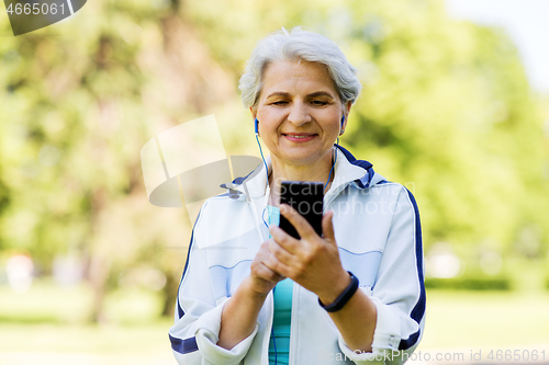 Image of sporty senior woman with earphones and smartphone