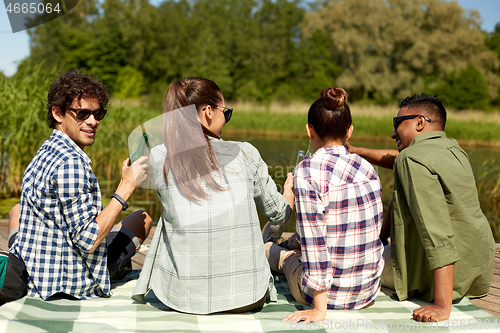 Image of friends drinking beer and cider on lake pier