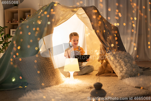 Image of little girl with tablet pc in kids tent at home