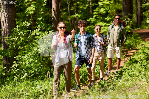 Image of group of friends with backpacks hiking in forest