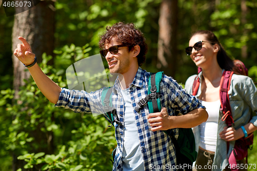 Image of mixed race couple with backpacks hiking in forest