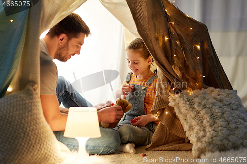 Image of happy family playing with toy in kids tent at home