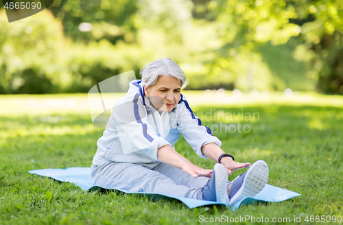 Image of happy senior woman exercising at summer park