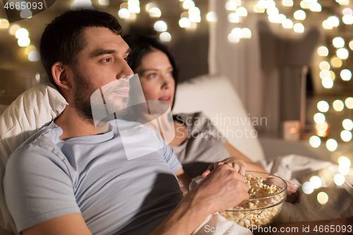 Image of couple with popcorn watching tv at night at home