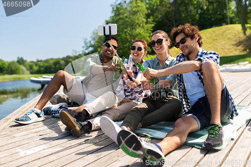 Image of friends with drinks taking selfie on lake pier