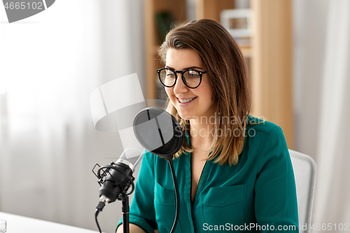 Image of woman with microphone recording podcast at studio