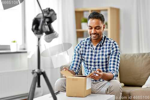 Image of male video blogger opening parcel box at home