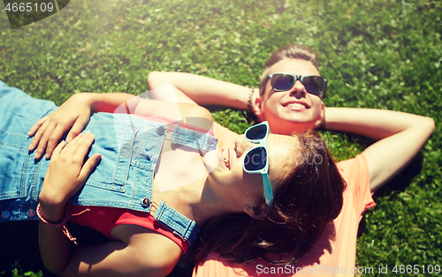 Image of happy teenage couple lying on grass at summer