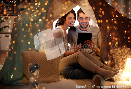 Image of happy couple with tablet pc in kids tent at home