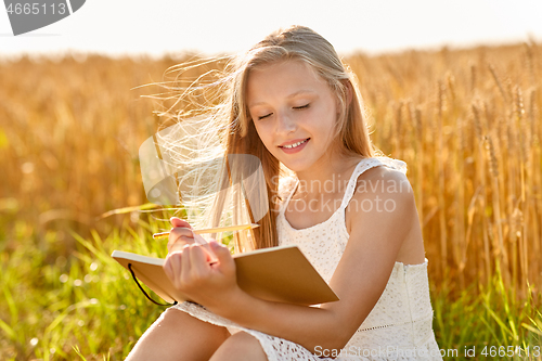 Image of smiling girl writing to diary on cereal field