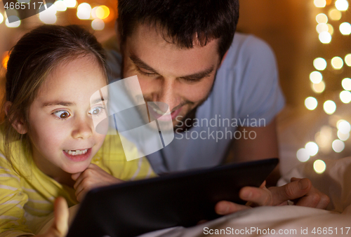 Image of family with tablet pc in bed at night at home