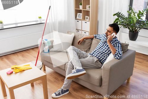 Image of man calling on smartphone after cleaning home