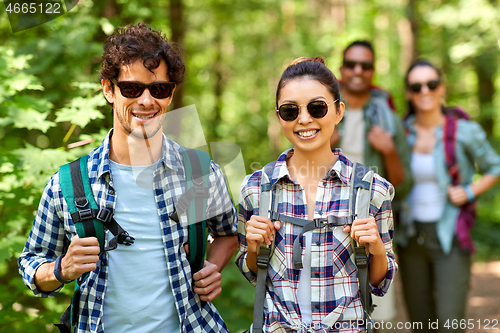 Image of group of friends with backpacks hiking in forest