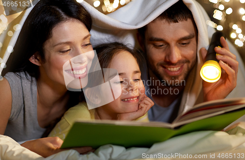 Image of happy family reading book in bed at night at home