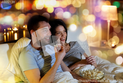 Image of couple with popcorn watching tv at night at home