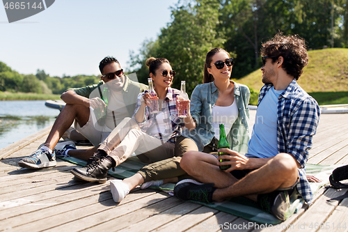 Image of friends drinking beer and cider on lake pier