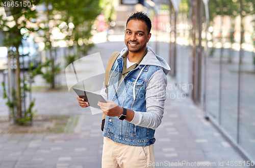 Image of man with tablet pc and backpack on city street