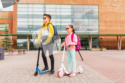 Image of school children with backpacks riding scooters