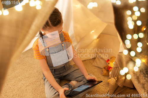 Image of little girl with tablet pc in kids tent at home