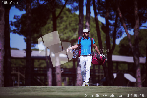 Image of golf player walking and carrying bag