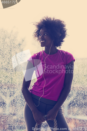 Image of portrait of young afro american woman in gym while listening mus