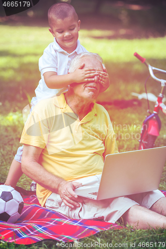 Image of grandfather and child using laptop