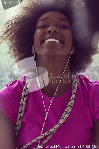 Image of portrait of young afro american woman in gym while listening mus