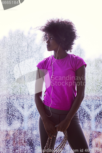 Image of portrait of young afro american woman in gym while listening mus