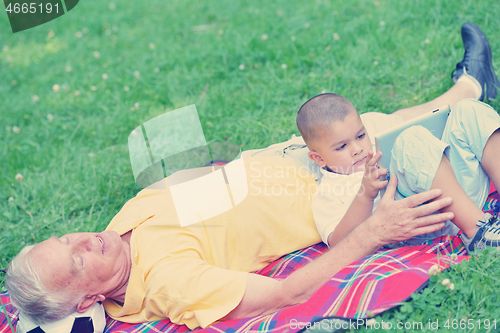 Image of grandfather and child in park using tablet