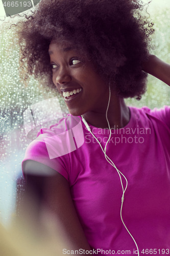 Image of portrait of young afro american woman in gym while listening mus