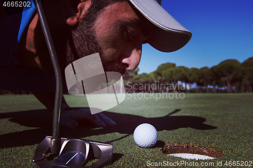 Image of golf player blowing ball in hole