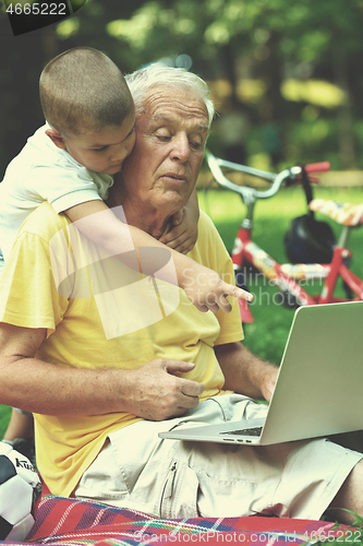 Image of grandfather and child using laptop