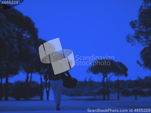 Image of golf player walking and carrying bag