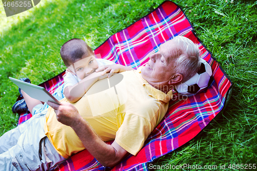 Image of grandfather and child in park using tablet