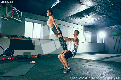 Image of Shot of young man and a woman standing in plank position at the gym