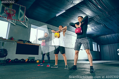 Image of The strong young fitness men in sportswear doing exercises at gym