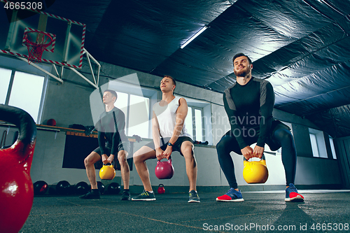 Image of The strong young fitness men in sportswear doing exercises at gym