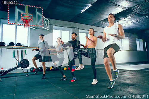 Image of Shot of young men and a woman standing in plank position at the gym