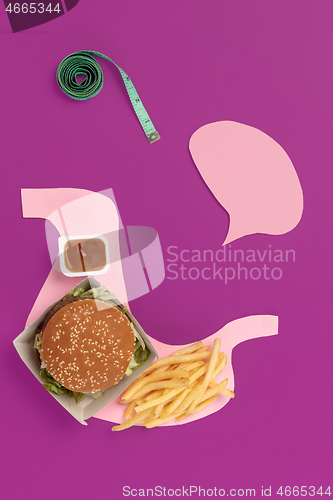 Image of I love fast food. French fries in the form of is stomach isolated on pink background