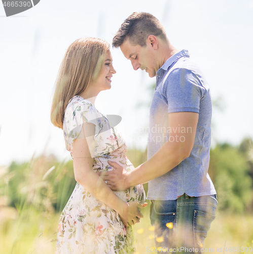 Image of Young happy pregnant couple hugging in nature.