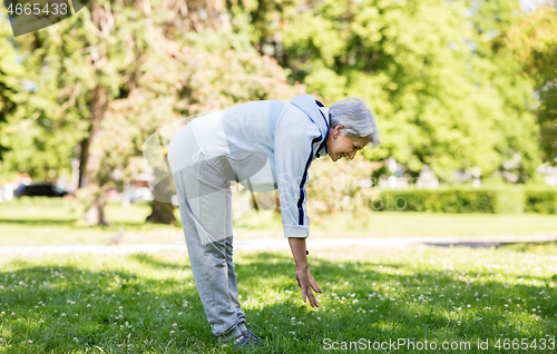 Image of happy senior woman exercising at summer park